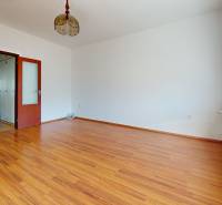 Pokoj v 3-pokojovém bytě s podlahou s dřevěným dekorem a velkým oknem.