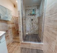 Koupelna v 3-pokojovém bytě s keramickými obklady a sprchovým koutem.