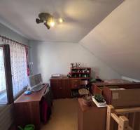 Podkrovní pokoj s pracovním stolem a postelí v rodinném domě.