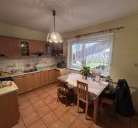 Kuchyně v rodinném domě s dřevěným dekorem a jídelním stolem.