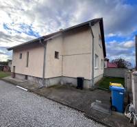 Rodinný dům v Zbechách s vedlejší cestou, trávníkem a modrou popelnicí.