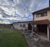 Rodinný dům v Zbechách s trávníkem, zahradou a kamenným chodníkem pod zamračenou oblohou.