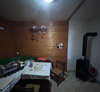 Rodinný dům s dřevěným obkladem stěn, kachlovými kamny a jídelním stolem.