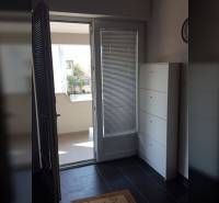 Vstup na balkon v rodinném domě s kachlovou podlahou a bílým nábytkem.