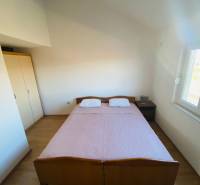 Ložnice v rodinném domě s postelí, nočním stolkem a podlahou s dřevěným dekorem.