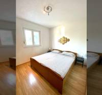 Ložnice v rodinném domě s manželskou postelí a podlahou s dřevěným dekorem.