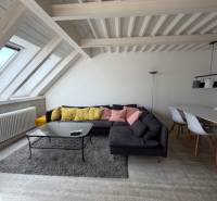 Obývací pokoj s podlahou s dřevěným dekorem, pohovkou a jídelním stolem ve 4-pokojovém bytě.