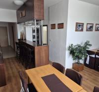 Interiér restaurace s dřevěným nábytkem, příjemným osvětlením a dekorativními rostlinami.