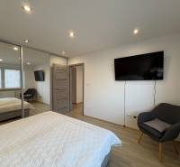 Dvoupokojový byt s TV, šatníkem a podlahou s dřevěným dekorem.