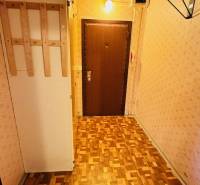 Chodba s podlahou s dřevěným dekorem a světlou tapetou v 2-pokojovém bytě.