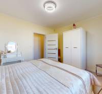 Ložnice s postelí, skříní a toaletním stolkem v rodinném domě.