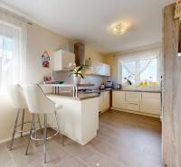 Kuchyně v rodinném domě s barovými židlemi a podlahou s dřevěným dekorem.