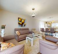 Obývací pokoj v rodinném domě s koženými sedačkami a skleněným stolkem.