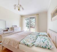 Ložnice v rodinném domě s postelí, toaletním stolkem a podlahou s dřevěným dekorem.