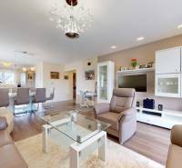 Obývací pokoj rodinného domu s koženým posezením a podlahou s dřevěným dekorem.