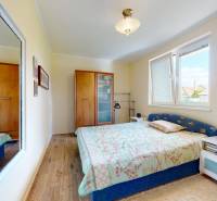 Ložnice v rodinném domě s podlahou s dřevěným dekorem, zrcadlem a postelí.