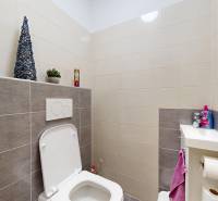 Toaleta s obklady a umyvadlem v rodinném domě.