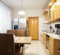 Kuchyně ve 3-pokojovém bytě s jídelním stolem, spotřebiči a světlým nábytkem.