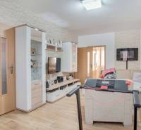 Obývací pokoj v 3pokojovém bytě s podlahou s dřevěným dekorem a rohovou sedačkou.