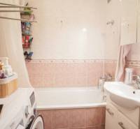 Koupelna ve 3-pokojovém bytě s vanou, umyvadlem, pračkou a úložnými prostory.