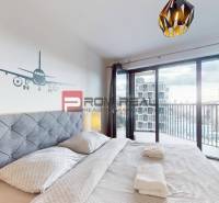 Ložnice v 2pokojovém bytě s balkonem a dekorací letadla na stěně.