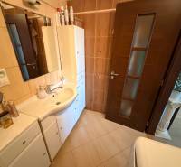 Koupelna v 3-pokojovém bytě s bílým nábytkem a tmavými dveřmi.