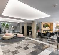 Kanceláře s černobílou podlahou, sloupy, sezením a kavárnou v interiéru.