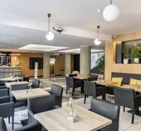 Kanceláře s podlahou s dřevěným dekorem, stoly, černými židlemi a rostlinami v Bratislavě.