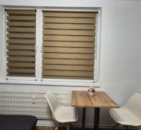 Jídelní kout s dřevěným stolkem a dvěma bílými židlemi v garsonce.