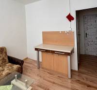 Garsonka s pohovkou, skleněným stolkem a podlahou s dřevěným dekorem.