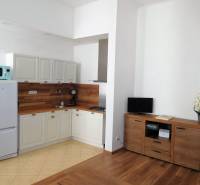 Kuchyňka v 2-pokojovém bytě, světlý interiér, podlaha s dřevěným dekorem, bílá lednička.