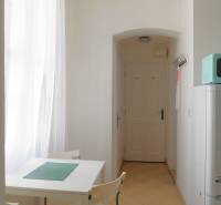 Jídelní kout se stolem, židlemi, bílou stěnou a zavěšeným světlem v 2-pokojovém bytě.