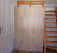 V 2-pokojovém bytě je šatní skříň s postelí a dřevěnými schody.