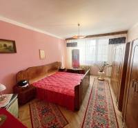 Ložnice ve 3pokojovém bytě s červenými doplňky a podlahou s dřevěným dekorem.