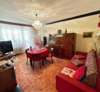 Obývací pokoj v 3-pokojovém bytě s kobercovým povrchem a dřevěným nábytkem.