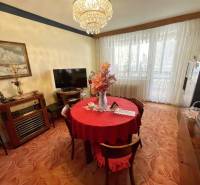 Jídelní část ve 3-pokojovém bytě s červeným ubrusem a velkými okny.