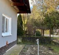 Rodinný dům v Mýtných Ludanech s boční zahrádkou a trávníkem, obklopený plotem.