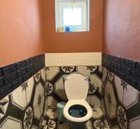 Koupelna v rodinném domě s výrazným geometrickým obkladem a oranžovými stěnami.