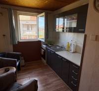 Kuchyně s podlahou s dřevěným dekorem a tmavými skříněmi v rodinném domě.