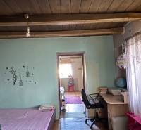 Pokoj s podlahou s dřevěným dekorem, postelí, pracovním stolem a dekoračními trámy na stropě.