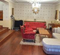 Obývací pokoj v rodinném domě s červeným nábytkem a televizorem na podlaze s dřevěným dekorem.