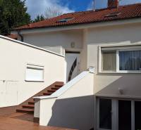 Rodinný dům v Komárně s bílou fasádou a červenou střechou.