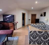 Obývací pokoj v rodinném domě s pohovkou, vzorovanou tapetou a televizí.