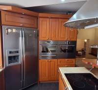 Kuchyně v rodinném domě s dřevěnými skříňkami a nerezovými spotřebiči.