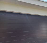 Garážová vrata u rodinného domu v Komárně, obklopená zelení.