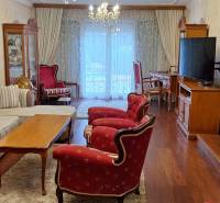 Obývací pokoj v rodinném domě s červenými křesly a podlahou s dřevěným dekorem.