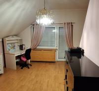 Pokoj s podlahou s dřevěným dekorem, nábytkem a lustrem v rodinném domě.