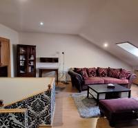 Obývací pokoj s pohovkami a vzorovanými stěnami, podlaha s dřevěným dekorem.