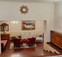 Luxusní interiér rodinného domu s dřevěným dekorem, pohovkou a uměleckými díly na stěnách.