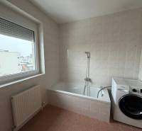 Koupelna ve 3pokojovém bytě s vanou, pračkou a velkým oknem.